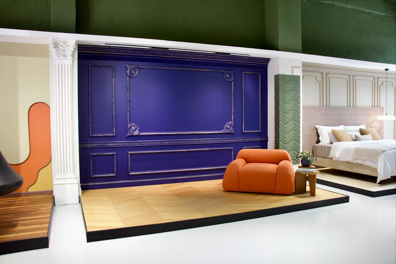 Salle bleue avec moulures, fauteuil orange et lit habillé de panneaux