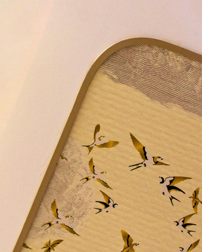 Détail du plafond décoratif avec un papier peint illustrant un envol d’oiseaux dorés, encadré par une plinthe flexible Orac SX194F formant un contour arrondi et raffiné.