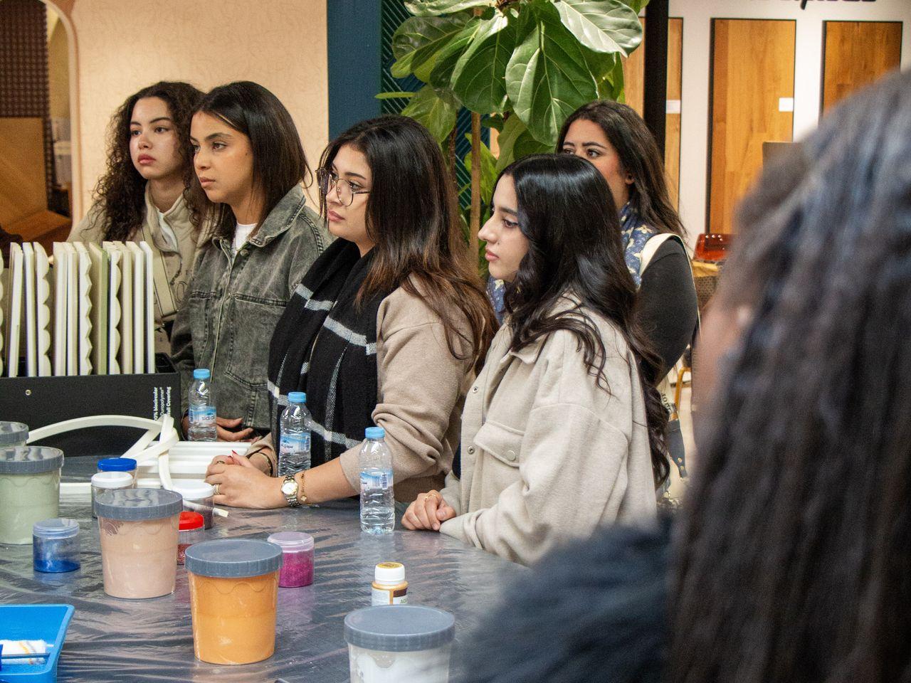 Photo de groupe de participants (étudiants et professionnels) posant devant un mur de marque éclairé 'ORAC MAROC' à la fin d'une Masterclass ou d'un workshop.